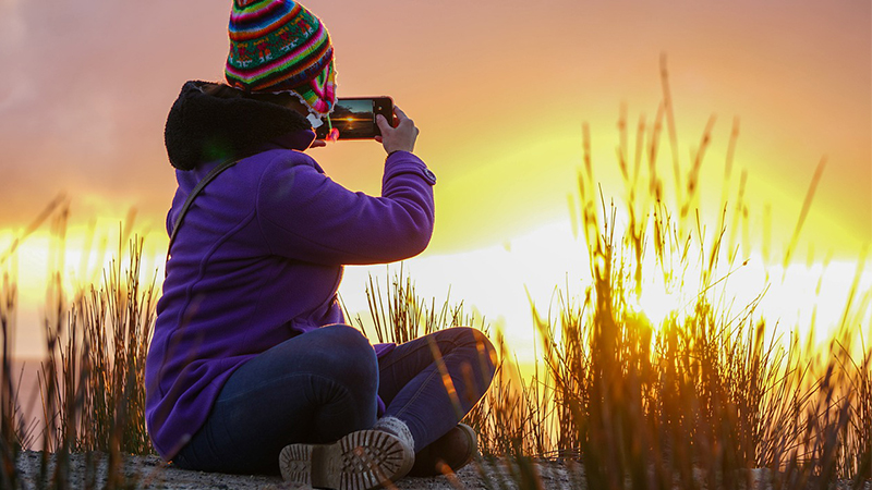 Femme en tenue outdoor avec un smartphone photographie le paysage